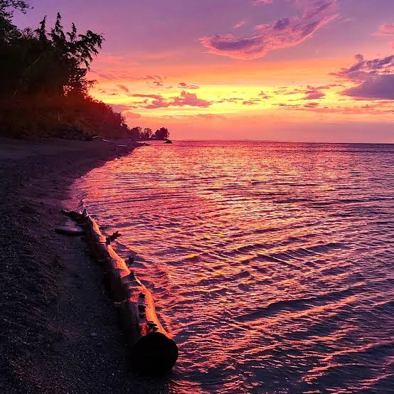Sunset over Lake Superior — a driftwood log on the shoreline, the Upper Peninsula of Michigan